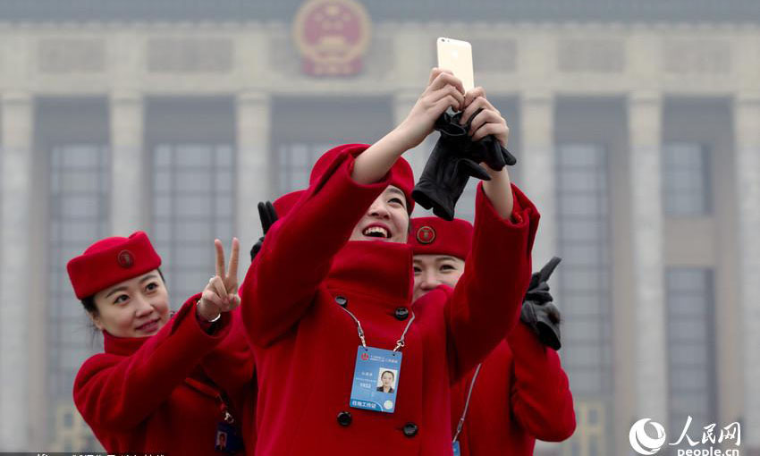 北京では3日、2014年の全国「両会」が開催された。北京天安門広場、人民大会堂では、美人のコンパニオンが注目を集めた。美人たちは手に携帯電話を持ち、記念撮影をしていた。