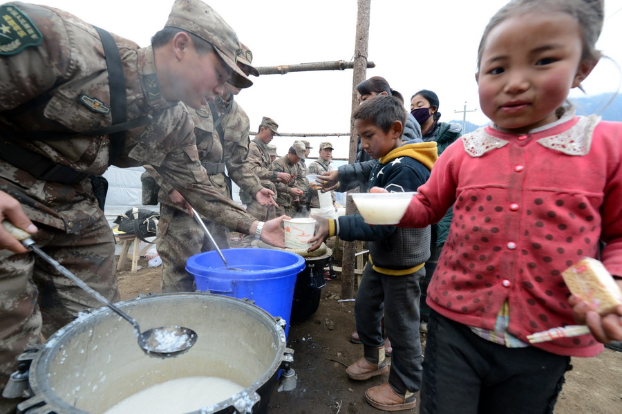 27日、被災地の子どもに朝食を配る解放軍救援隊。