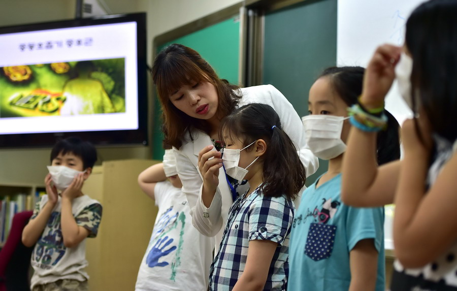 MERS予防の授業中に生徒にマスクを着ける教師（6月3日、韓国ソウルの小学校にて）