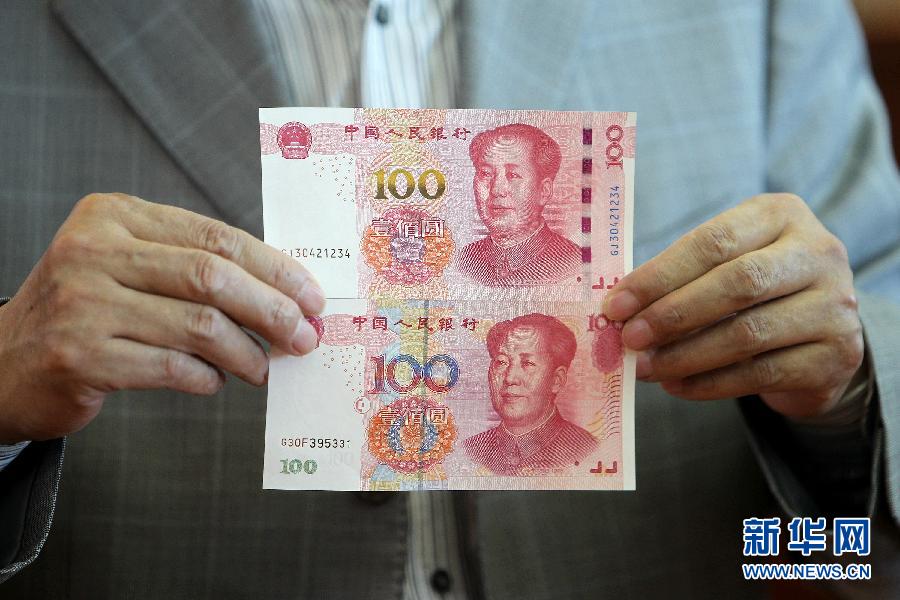 事務所で新版の百元紙幣（上）と旧版を比較する中国紙幣印刷造幣総公司の邵国偉技術ディレクター。