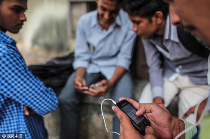 インド・ムンバイにてスマートフォンでインターネットをする通行人（CFP）。