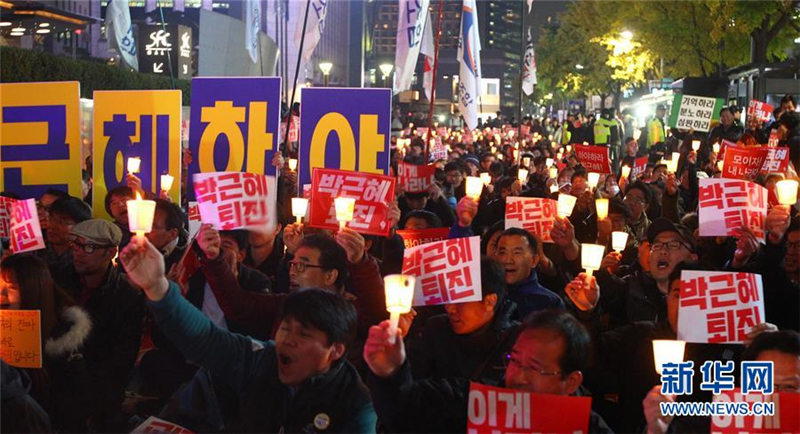 ソウルの清渓川広場付近で「朴槿恵退陣」と書かれたプラカードを掲げて、デモに参加する市民たち（撮影・姚■琳（■は王へんに其）