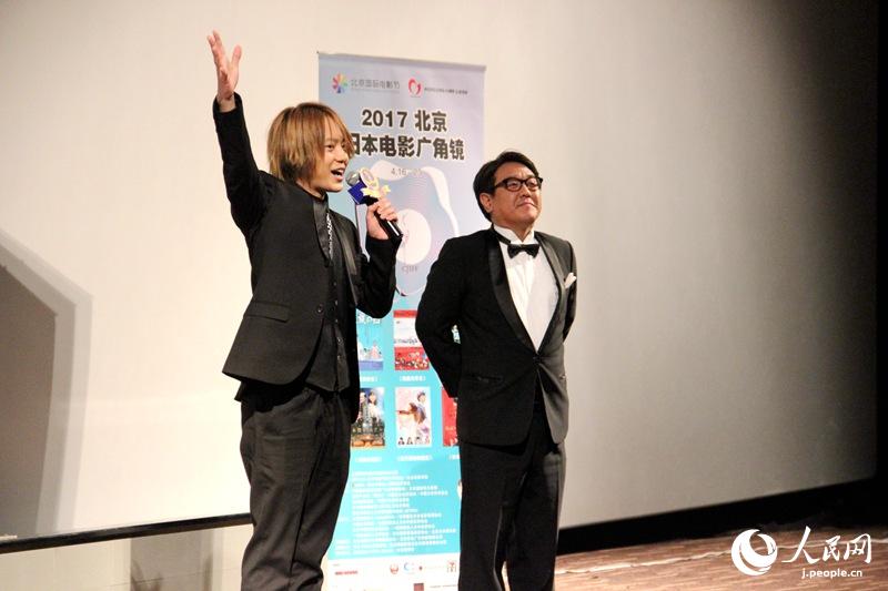 ステージ上で舞台挨拶を行う主演の佐藤流司さんと堀内博志監督。