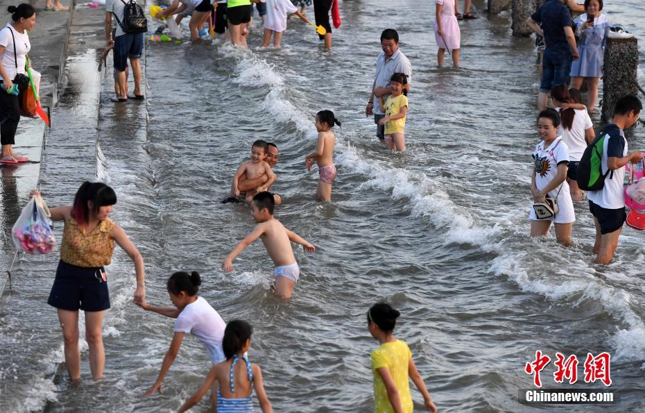 猛暑が続く厦門市、市民たちは海辺で水遊び