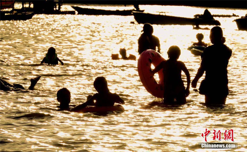 夕日に照らされ「火の海」のような水辺で遊ぶ市民たち　福建省