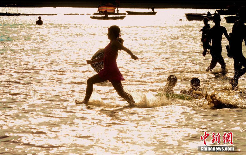 夕日に照らされ「火の海」のような水辺で遊ぶ市民たち　福建省