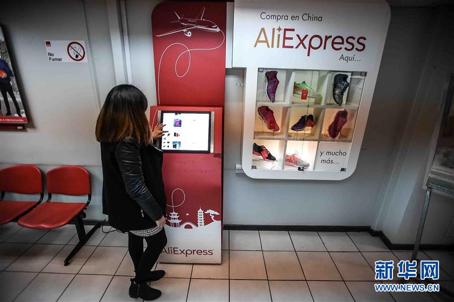 チリの首都・サンティアゴにあるチリ郵便局の営業所で、タッチパネルでアリエクスプレスのサイトを閲覧する女性。タッチパネルの右横にある同サイトのショーケースには、中国のスポーツブランド李寧のランニングシューズ8足がディスプレイされている。（8月25日撮影・Jorge）。
