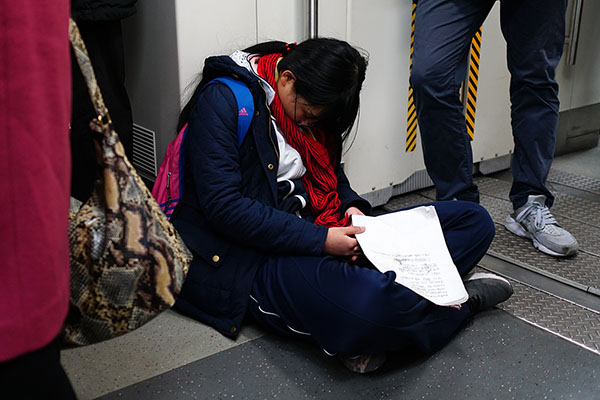 地下鉄でプリントを握りしめたまま眠る中学生を気遣う乗客たち　北京市