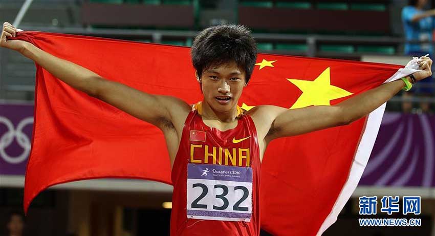 第1回ユースオリンピックの男子200メートル決勝で21秒22の記録を出して優勝した後、国旗を掲げて喜びを示す謝震業選手（2010年8月22日、撮影・廖宇傑）。