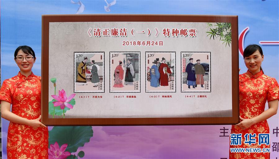 福建省邵武市で行われた「清正廉潔（一）」記念切手の発行イベントで、記念切手のデザインを見せるスタッフたち（6月24日、撮影・張国俊）。