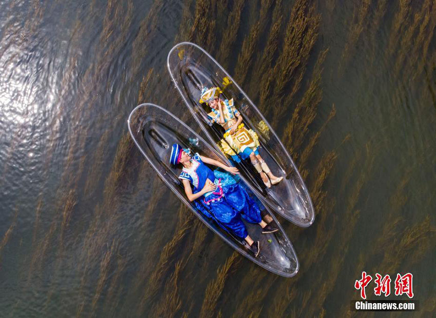透明なボートの上で絵画のような景色を堪能する少数民族の若者たち