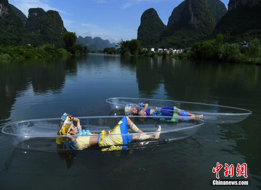 透明なボートの上で絵画のような景色を堪能する少数民族の若者たち　桂林