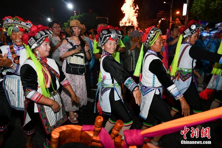 雨の中、「松明祭」を祝い歌って踊るイ族の人々　雲南省昆明市