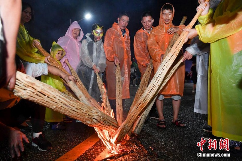 雨の中、「松明祭」を祝い歌って踊るイ族の人々　雲南省昆明市