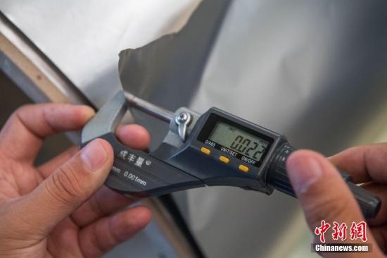 山西省太原市で8日、精密計器で厚さ0.02ミリのステンレスを測る太鋼精密帯鋼公司の従業員（撮影・韋亮）。