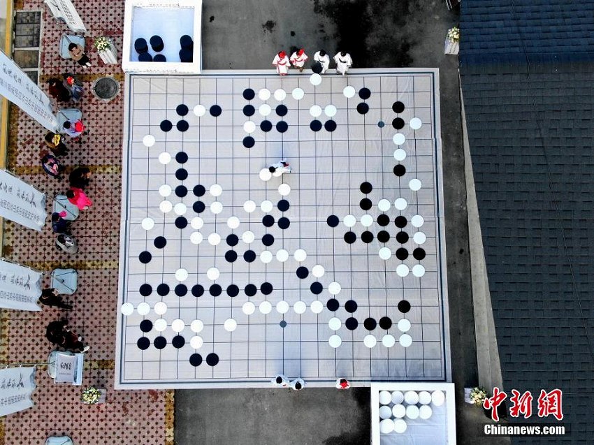 百メートル四方の碁盤上で碁石を動かす小さな棋士たち