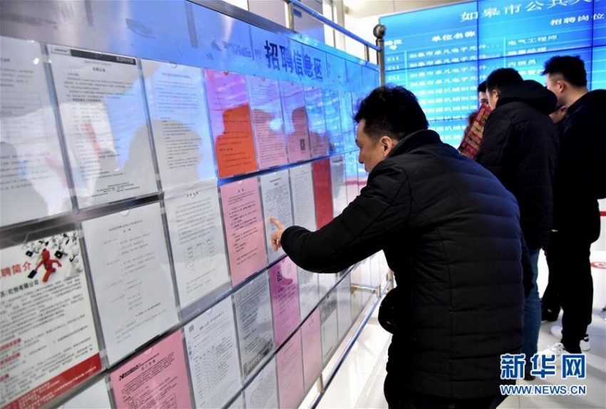 江蘇省南通如皋市の合同就職説明会で、新入社員募集の情報を見る男性（2月11日撮影）。