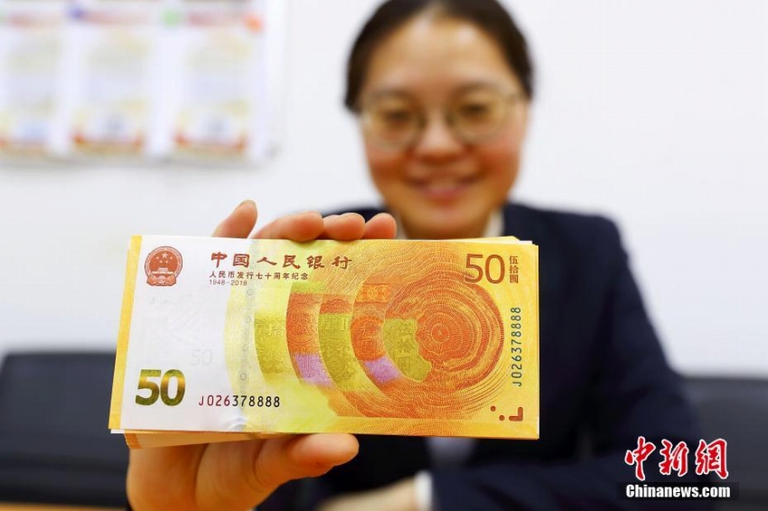 人民元発行70周年記念紙幣を見せる山西省太原市のある銀行の銀行員(撮影・張雲)。