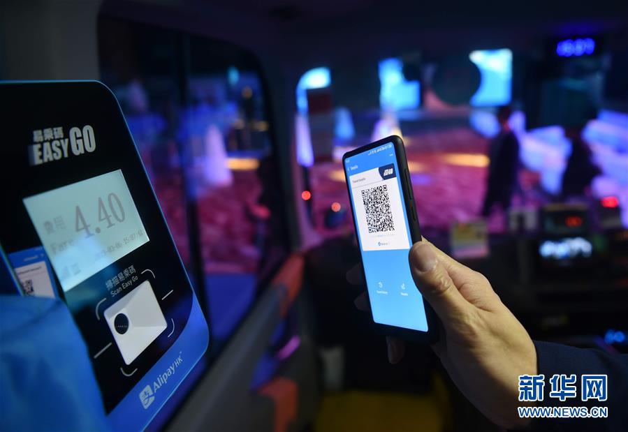 香港会議展覧センターで携帯による乗車料金の支払いが可能なミニバスで支払いコードを読み取る体験者（3月6日撮影・王申）。