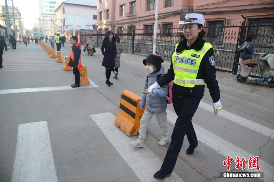 子供の手を引いて一緒に道路を横断する交通警察官（撮影・劉文華）。