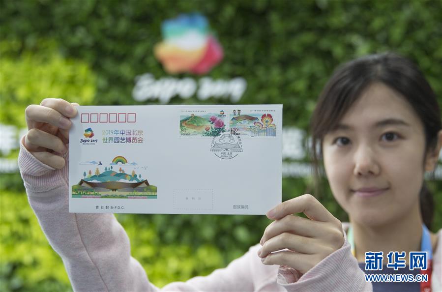 4月29日、「2019年北京世界園芸博覧会」のプレスセンターで記念切手を掲げる女性記者（撮影・侯東涛）。