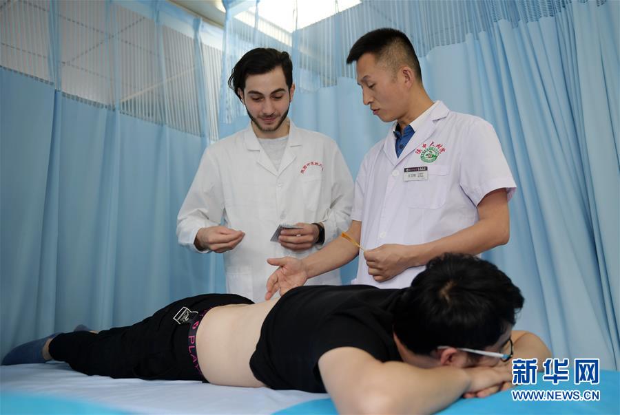 6月10日、陝西中医薬大学付属病院鍼灸マッサージ科の王衛剛主任の指導のもとで鍼灸の練習をするジョニーさん（写真左、撮影・李一博）。