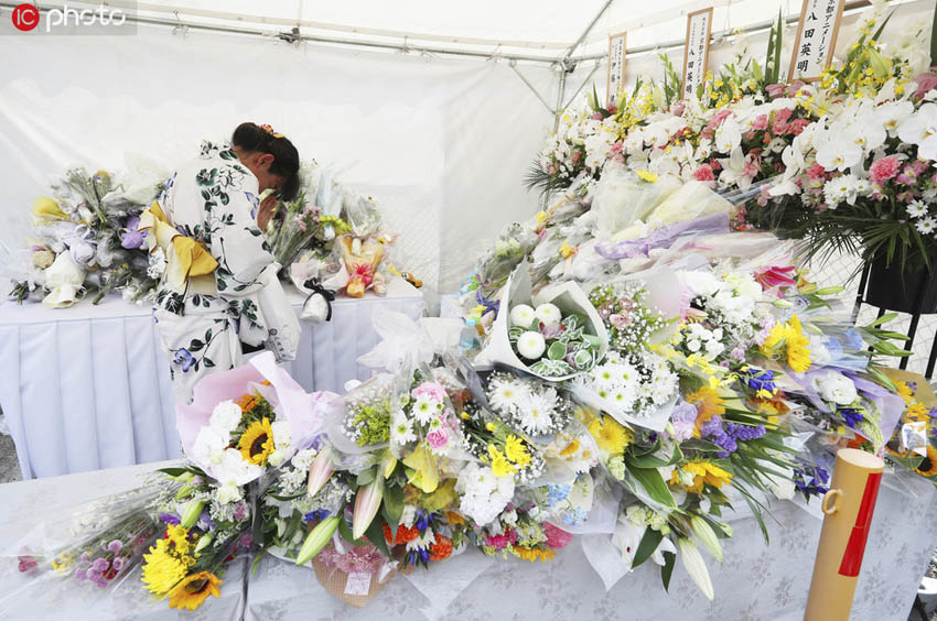 現地時間23日、京都市伏見区にある京都アニメーションの第1スタジオ火災現場近くに設けられた献花台で死者を悼む女性（写真著作権は東方ICが所有のため転載禁止）。