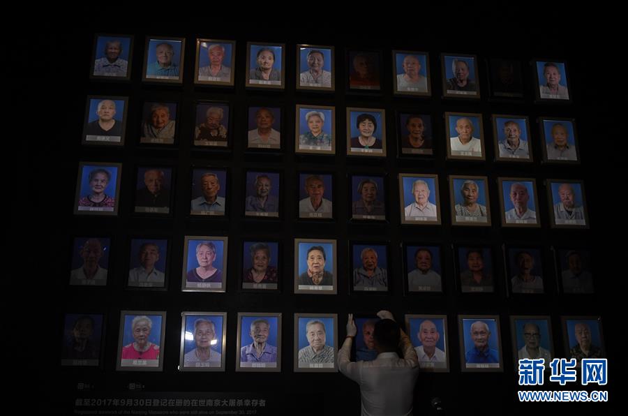 中国侵略日本軍南京大虐殺遭難同胞紀念館で7月31日、館内にある南京大虐殺生存者の写真の壁に掲げられた万秀英さんの写真の灯りが消される様子（撮影・季春鵬）。