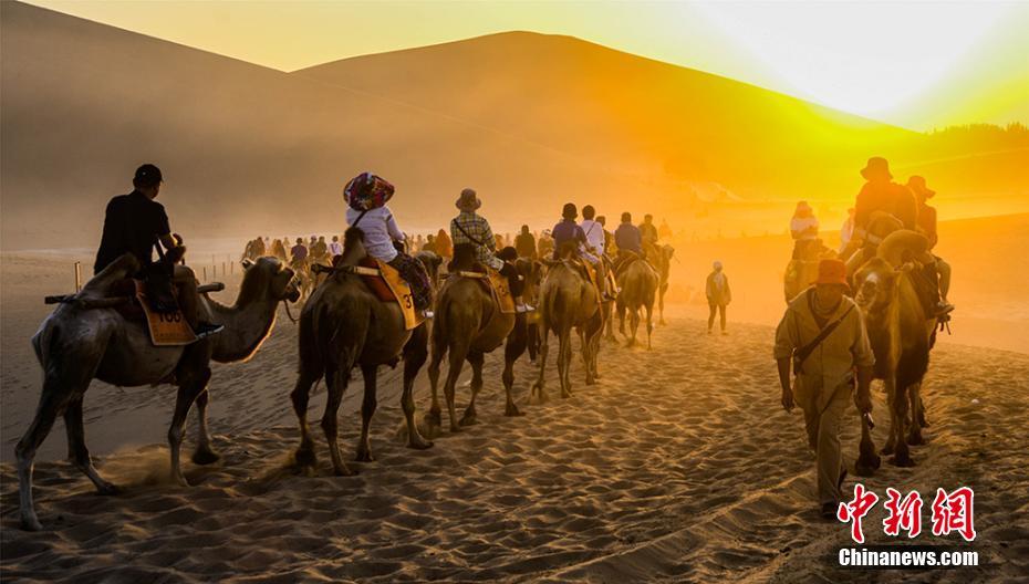 ラクダに乗り鳴沙山砂漠を遊覧、シルクロードの風情を心行くまで体験する観光客(撮影・王斌銀)。