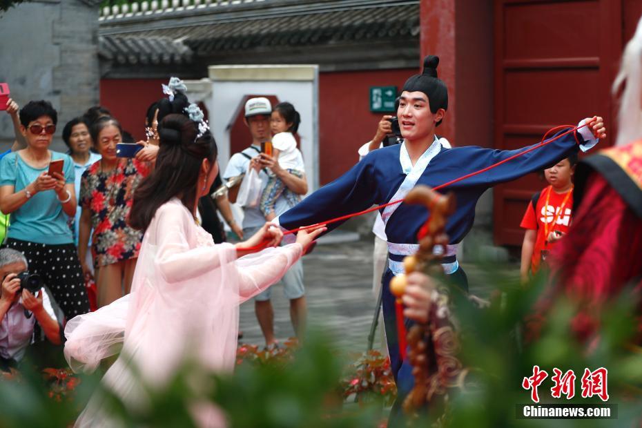伝統的な衣装を着て縁結びの神「月老」が赤い糸で縁結びをするシーンを演じる俳優。