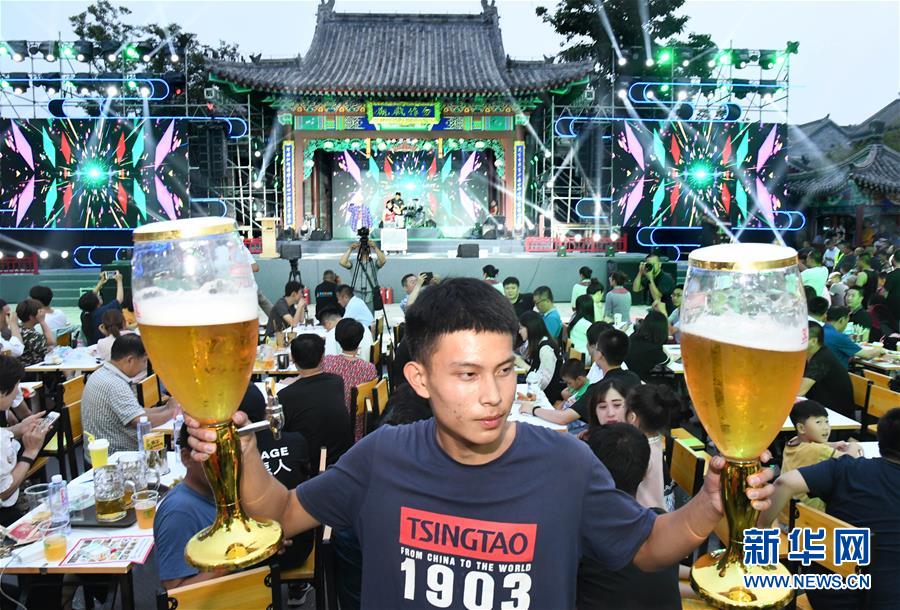 山東省青島市の国際ビール祭り(即墨古城会場)で大きなビールグラスを両手に持つ男性（7月12日撮影・李紫恒）。
