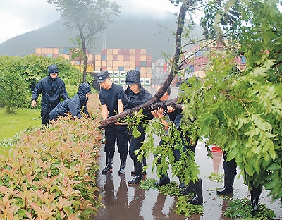 雨の中、埠頭一帯をパトロールし、道路の障害物を整理する浙江穿山出入境辺防検査所の警察官たち（撮影・方千勲）。