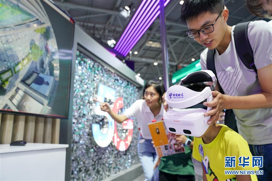 中国電信の展示ブースで、家族に付き添われ、VRデバイスを使い5Gバーチャルシーンを体験する男の子。