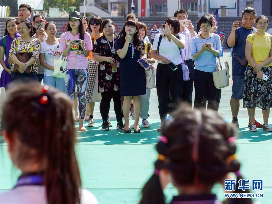 9月1日、北京市東城区灯市口小学・灯市口キャンパスで行われた入学式終了後の記念撮影をする新一年生の横で写真を撮る保護者ら。中には、子供にポーズのとりかたを教える保護者の姿も (撮影・沈伯韓)。