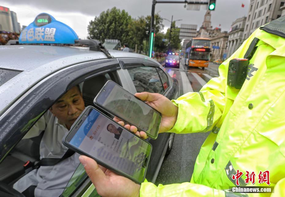  ドライバーの電子版運転免許証を確認する警察官 (撮影・殷立勤)。