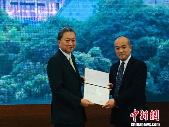 任命書を授与した武漢大学の竇賢康学長（写真右）と鳩山由紀夫氏（写真左、撮影・馬芙蓉）。