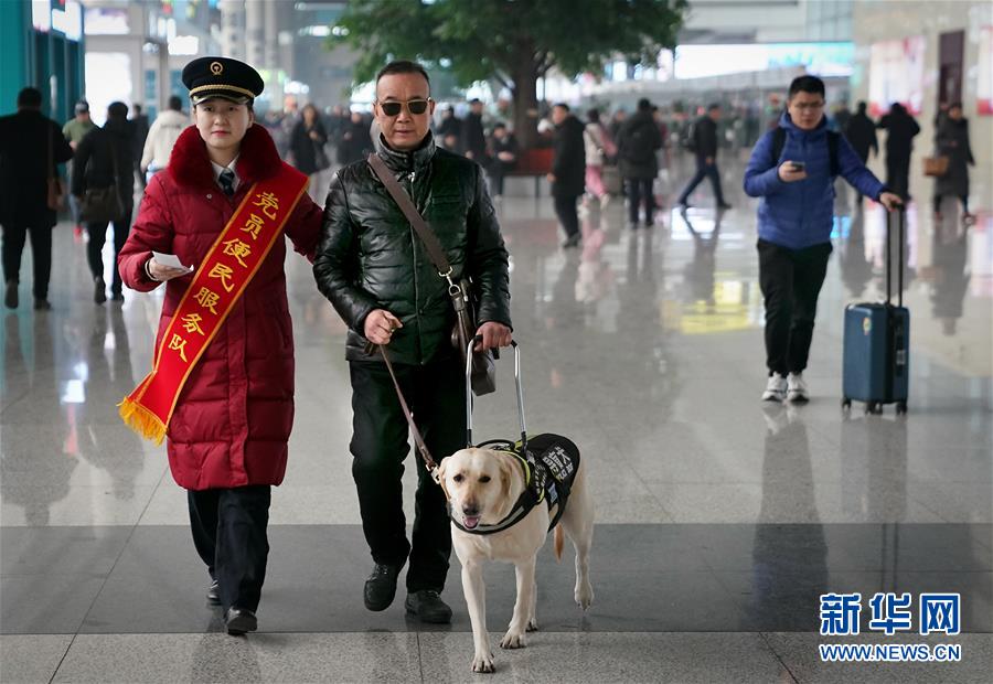 目の不自由な乗客の靳さんと盲導犬の「小七」を駅構内の待合室まで案内する鄭州東駅のスタッフ（1月14日に撮影・李安）。