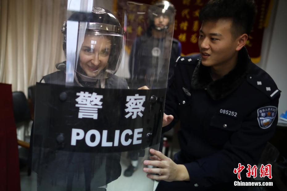 1月15日、警察官の指導のもと、警備装備の着用体験をする留学生（撮影・ 泱波）