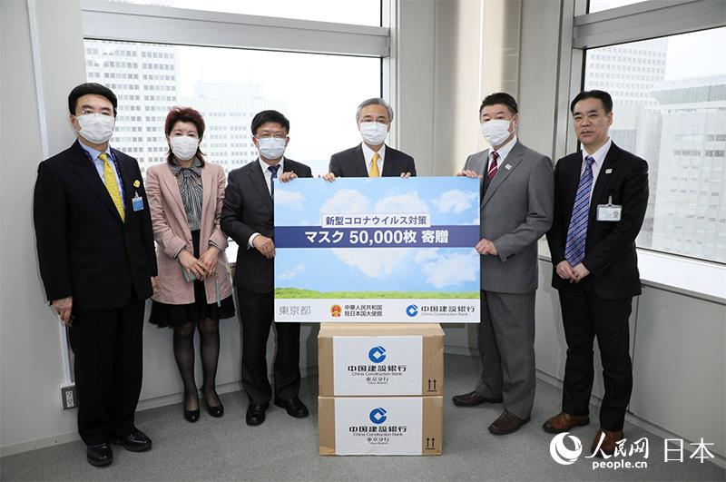  東京都庁の代表にマスクを寄贈する在日本中国大使館の宋耀明経済商務公使（写真右から3番目）、在日中国企業協会の王家馴会長（写真一番左）、中国建設銀行東京支店の解陸一支店長（写真左から3番目）、王玉潔副支店長（写真左から2番目）。（画像は中国建設銀行東京支店が提供）