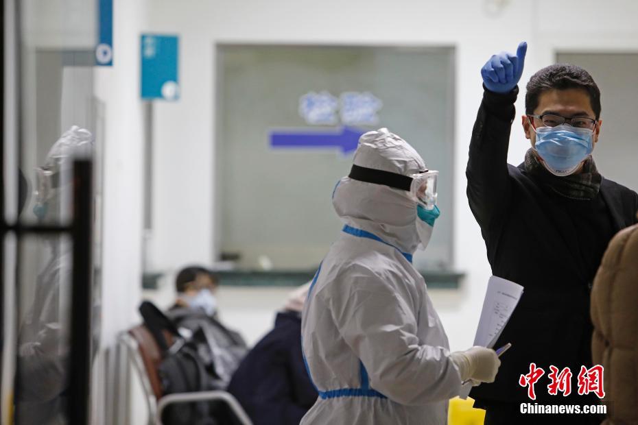 浦東新区人民病院の医療従事者に対し、親指を立てるジェスチャーで「いいね！」の気持ちを示す浦東空港にから入国した発熱者（撮影・殷立勤）。
