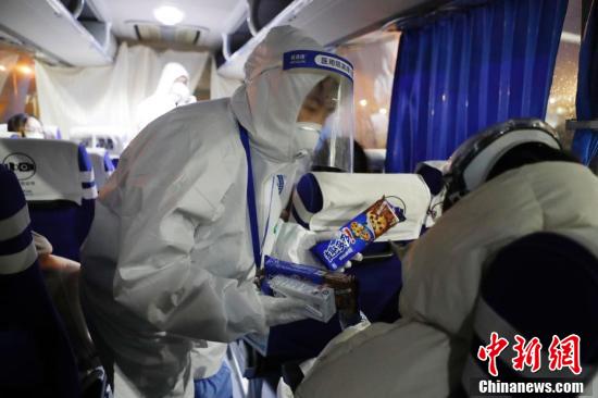 3月29日、緊急移送車の車内で、入境者にビスケットや牛乳、ミネラルウォーターを配る浦東空港交通保障担当職員（撮影・殷立勤）。