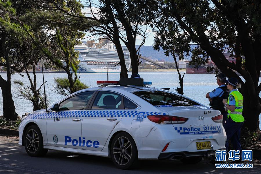 4月6日、オーストラリア・ケンブラ港に入港しているクルーズ船「ルビー・プリンセス」号を眺める警官2名（撮影・朱宏業）。