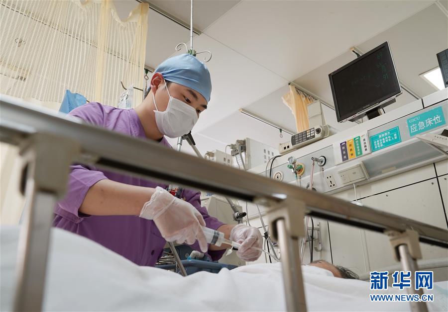 5月10日、上海市普陀区センター病院集中治療室で、患者の鼻に挿入したチューブから流動食を流し込む23歳の看護師・範磊磊さん。男性看護師チームのほとんどは、「90後（1990年代生まれ）」（撮影・劉穎）。