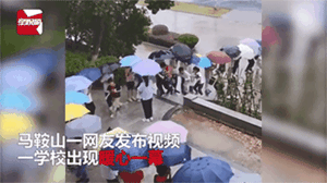 暴雨の中、高学年生が低学年生のために作った思いやりたっぷりの「傘の通路」