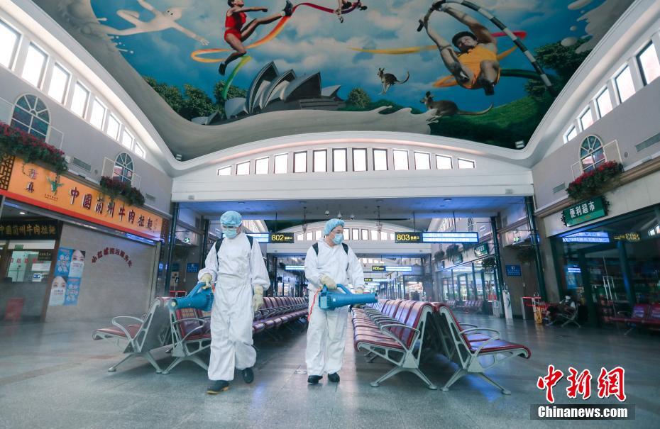 6月18日、北京駅構内で、防護服を着用して消毒作業を行う職員（撮影・賈天勇）。