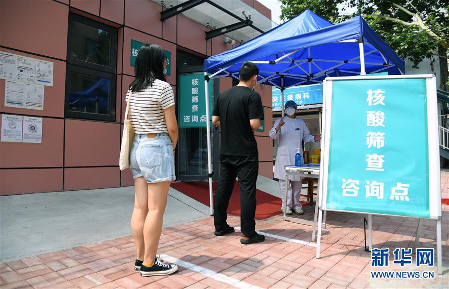 6月20日、北京市海淀病院で、市民にPCR検査の検体採取の流れについて市民に説明する医療関係者（写真右、撮影・任超）。