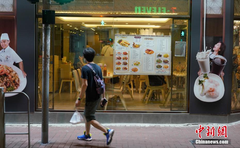 7月15日夜、テイクアウトした食品を手に、レストランの前を通る市民（撮影・張煒）。