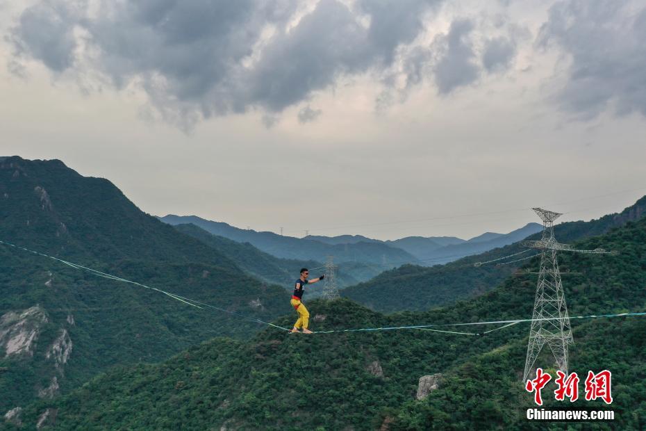 7月19日、広東省清遠市にある黄騰峡天門ガラス吊橋の上方で、素足でスラックラインのデモンストレーションを行うスラックライン選手の施海林さん（ドローンによる撮影・陳驥旻）。