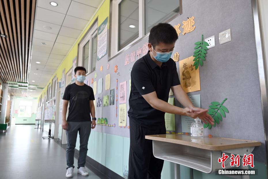 8月24日、北京教育学院附属豊台実験学校で、教室に入る前に手の消毒を行う教職員。同校の全教室の入口には、新学期開始後に生徒が使用できるように、消毒ジェルなどの防疫用品が設置されている（撮影・張興龍）。