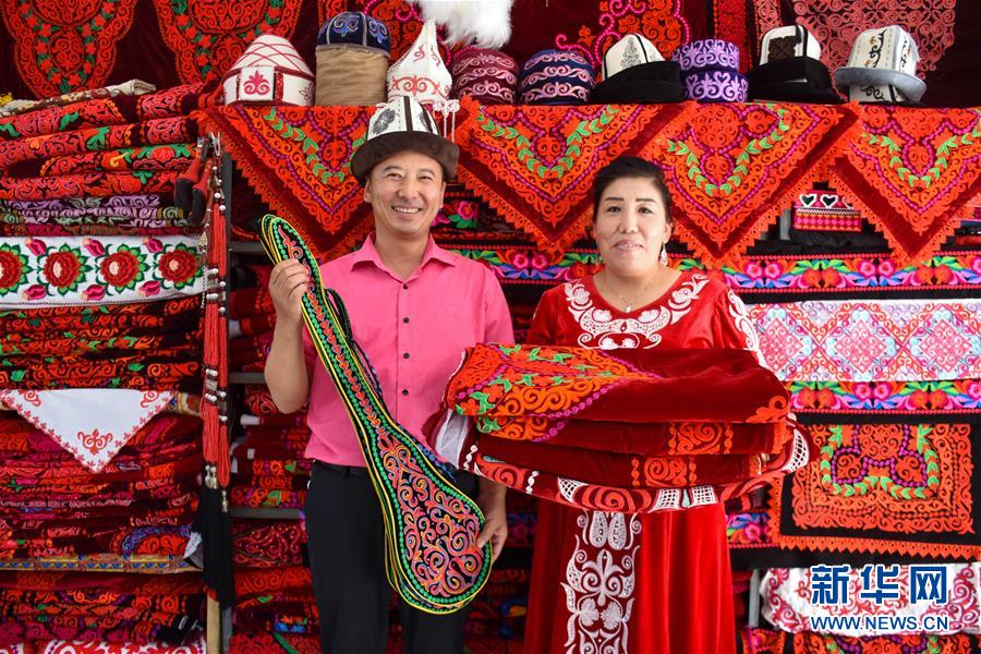 9月20日、新疆維吾爾（ウイグル）自治区阿克陶（アクト）県にある絲路佳苑手工業合作社で、ハンドメイド刺繍製品を見せる艾拉努爾·吾普爾さん（写真右）と夫の乃再爾・依迪西さん（写真左、撮影・高晗）。